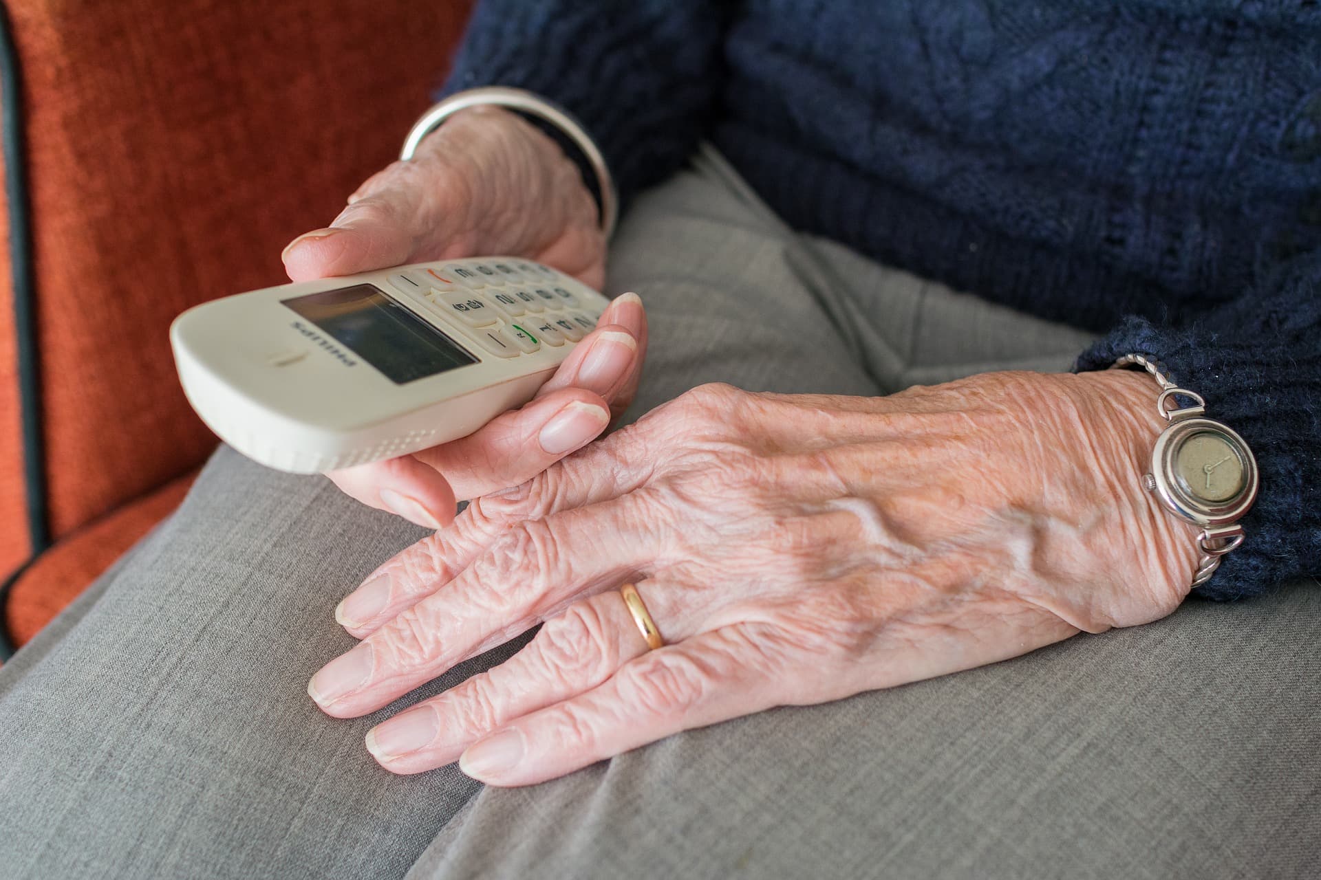 An older person holding a telephone as a symbol of family contact and reassurance.