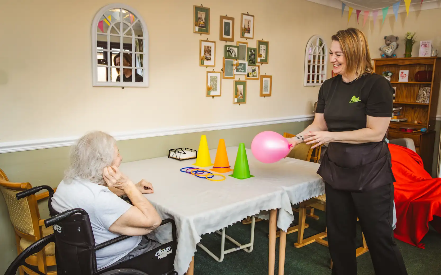 A Hollyman team member smiling with a resident during an activity.